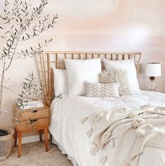 a bedroom with a tree painted on the wall and white bedding, along with two nightstands