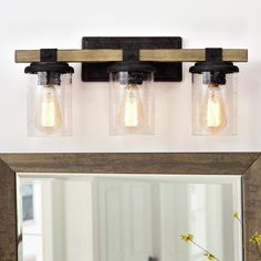 a bathroom vanity with three lights and a mirror on the wall next to vases