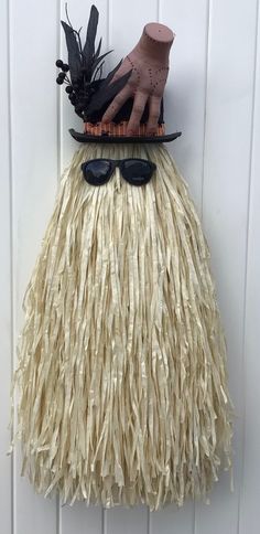 a hat and sunglasses on top of a fake grass skirt hanging from a hook in a door