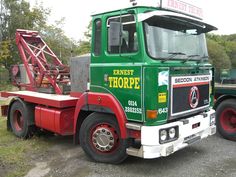 a green and red truck is parked on the side of the road near other trucks