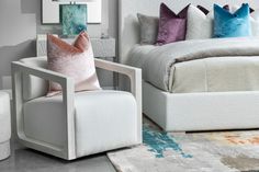 a white chair sitting next to a bed with pillows on it's backrest