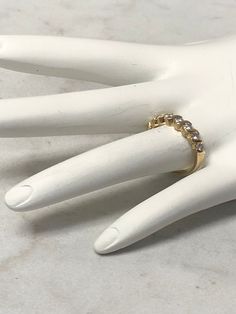 a white mannequin hand with a gold ring on it's left hand