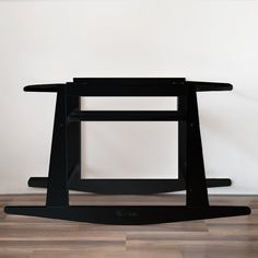 a black table sitting on top of a hard wood floor next to a white wall