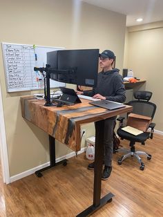 a man sitting at a computer desk in front of a monitor on top of a wooden table