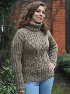 a woman standing outside wearing a sweater and jeans