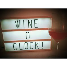 a wine glass sitting next to a sign that says wine o'clock