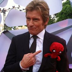 a man in a suit pointing at a spiderman stuffed animal