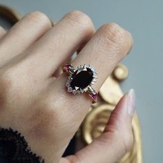 a close up of a person's hand wearing a ring with a black stone