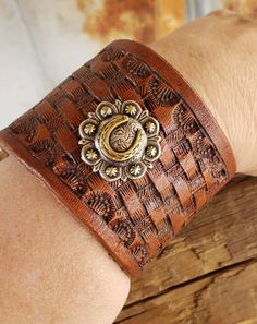 This gorgeous leather cuff bracelet is basket stamped with a beautiful horse shoe concho added.  The cuff is 2" wide and snaps closed fitting up to an 8 inch wrist. If you have a small wrist and would like us to add an additional snap, please let us know. Vintage Hand-tooled Leather Cuff Bracelet, Handmade Western Style Cuff Bracelets, Vintage Brown Jewelry For Rodeo, Western Style Leather Bracelet With Concho As Gift, Adjustable Hand Tooled Western Leather Bracelet, Western Style Leather Bracelet With Concho, Western Style Leather Concho Bracelet As Gift, Western Hand Tooled Cuff Bracelet As Gift, Brown Hand Tooled Western Bracelets