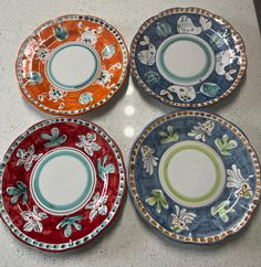 four colorful plates sitting on top of a counter