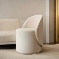 a white chair sitting on top of a carpeted floor next to a couch and table