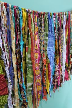 multicolored scarves are hanging on the wall in front of a blue wall