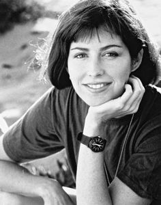 a black and white photo of a woman with her hand on her chin, smiling