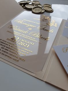 the wedding stationery is set on top of some gold and silver paper with coins