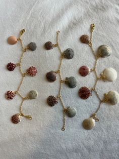 several seashells are arranged on a white sheet with gold chain necklaces and pendants