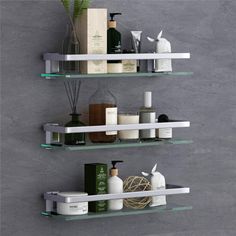 two glass shelves with bottles, soaps and other personal care items on them against a gray wall