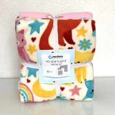 two baby blankets sitting next to each other on top of a white table with a blue tag