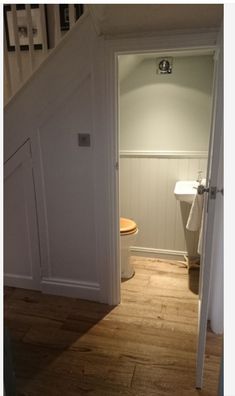 an open door leading to a bathroom with a sink and toilet in the corner next to stairs