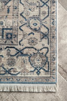 a blue and beige rug with fringes on the floor in front of a tile floor