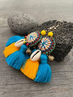 Unique fun and colorful earrings. Made with yellow and blue tassels and a beautiful round center piece made with different fabrics and strings, the earrings are adorned with beads, brass bells and shells. This pair will rock your outfit. Fun and easy to wear as they are super light. The earrings are 6cm- 2.40inch long 5.3cm- 2.10inch wide This timeless pair will brighten up your days! To see more unique and fun colorful tassel earrings, click the link below https://www.etsy.com/shop/AkashiJewelr Boho Tassel Earrings, Blue Bohemian Earrings With Latkans, Multicolor Tassel Earrings With Latkans For Summer, Multicolor Latkans Tassel Earrings For Summer, Bohemian Tassel Earrings With Fringe For Vacation, Bohemian Blue Earrings With Latkans, Blue Fringe Earrings For Festivals, Blue Bohemian Dangle Tassel Earrings, Bohemian Blue Dangle Tassel Earrings