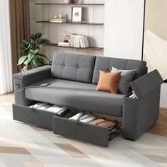 a grey couch with storage underneath it in front of a book shelf filled with books