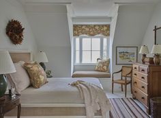 a bedroom with white walls and carpeted flooring, along with two windows that have roman shades on them