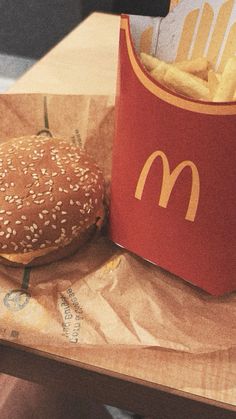 a hamburger and french fries in a paper bag sitting on a table next to a drink