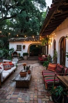 an outdoor living area with couches, tables and potted plants