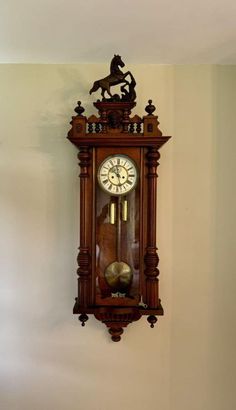 an old wooden clock mounted to the wall with a horse on it's face