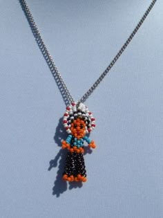 a beaded necklace with an orange, black and white doll hanging from it's center