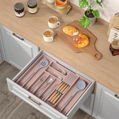 an open drawer with utensils and spoons in it on a kitchen counter