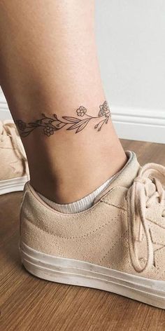 a woman's foot with a small flower tattoo on the side of her ankle