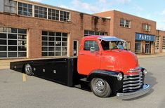 an orange and black truck parked in front of a building