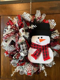 a christmas wreath with a snowman on it and red, white and black ribbons