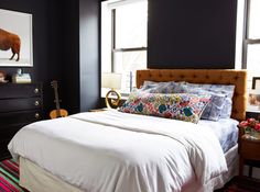 a bedroom with black walls, white bedding and an animal print on the wall