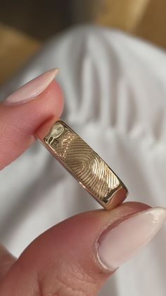 a close up of a person's hand holding a gold ring with finger prints on it