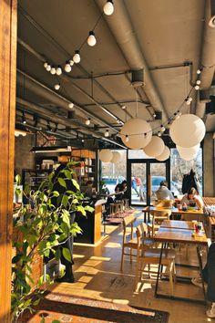 people sitting at tables in a restaurant with lots of light bulbs hanging from the ceiling