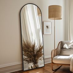 a large mirror sitting on top of a wooden floor next to a chair and lamp