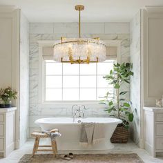 a white bath tub sitting under a chandelier in a bathroom