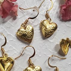 Elevate your style with our Gold Heart Locket Earrings, a delightful blend of charm and elegance. Each earring showcases a heart-shaped locket with an intricate floral design, infusing your look with a touch of romance and a delicate, feminine aesthetic. Crafted with nickel-free earring posts, these earrings prioritize comfort and safety, making them the perfect choice for any occasion. Embrace beauty and sophistication with these exquisite accessories. Heart-shaped Metal Earrings For Wedding, Heart Charm Metal Earrings For Gift, Metal Heart Earrings For Wedding, Metal Heart Pendant Earrings For Gift, Metal Heart Earrings With Matching Pair For Wedding, Heart Charm Drop Earrings For Mother's Day, Elegant Gold Flower Earrings For Valentine's Day, Mother's Day Heart Charm Drop Earrings, Wedding Metal Heart Earrings