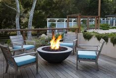 a fire pit sitting on top of a wooden deck next to two chairs and a table