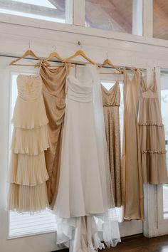 several dresses hanging on a rack in front of a window