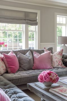 a living room filled with lots of furniture and pink flowers on the coffee table in front of it