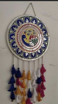 a colorful wall hanging with tassels on it's sides and a circular mirror in the middle