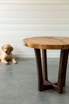 a dog laying on the floor next to a table that is made out of wood