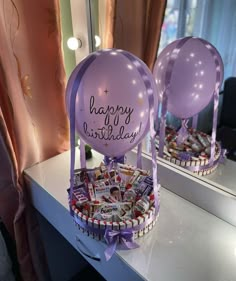 two purple balloons sitting on top of a table next to a mirror with the words happy birthday written on it