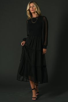 The Remi Ribbed Maxi Dress is trendy and timeless in classic black. Featuring a chic round neckline, sheer puffed sleeves with sweater knit cuffs, and a maxi-length skirt adorned with tiered tulle overlay, this dress is a sophisticated statement piece for any occasion. Black Midi Dress With Elastic Sleeves For Fall, Solid Long Sleeve Dress For Layering, Long Sleeve Solid Dress For Layering, Black Midi Dress With Bishop Sleeves For Fall, Chic Solid Dresses For Layering, Elegant Dresses For Fall Layering, Elegant Fall Dresses For Layering, Elegant Evening Dresses With Smocked Cuffs, Chic Midi Dress With Smocked Cuffs For Work