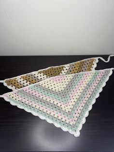 two pieces of crochet sitting on top of a wooden table