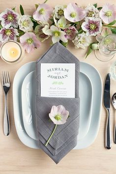 a place setting with napkins, silverware and flowers