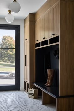 an empty room with wooden cabinets and shoes on the floor, near a large window